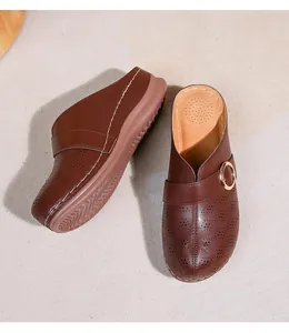 Détail de mules en cuir marron avec découpes en diamant et boucle métallique dorée