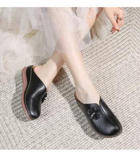 Close-up of black hollow-out platform mules featuring laser-cut floral patterns and stitching