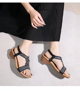 Dettaglio dei sandali neri con zeppa decorati con strass e cinturino elastico sul tallone