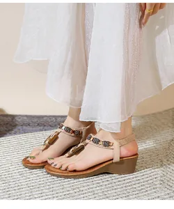 Detail of bohemian wedge sandals with ethnic metallic beads and elastic strap on a model