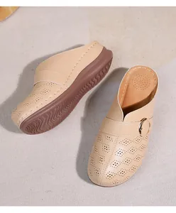 Détail de mules beiges ajourées avec boucle en métal doré et semelle compensée marron