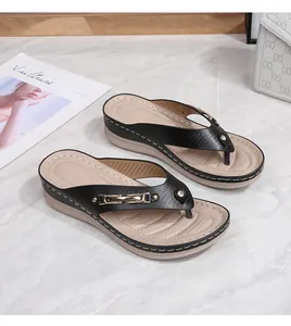 Detail view of black wedge thong sandals with gold buckles and laser-cut patterns