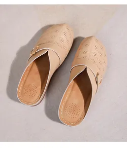 Détail du sabot beige ajouré avec perforations florales et boucle dorée décorative