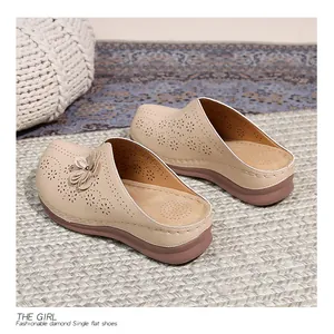 Detail of hollow-out flower pattern and laser-cut design on beige platform mule shoes