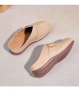 Détail du motif floral ajouré et boucle en métal sur mules compensées beiges pour femmes