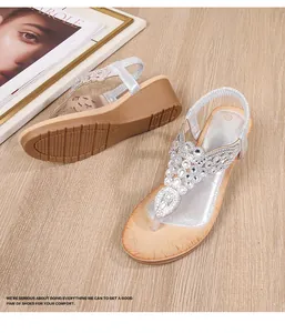 Detail of silver bohemian wedge sandals featuring shimmering rhinestones and T-strap design