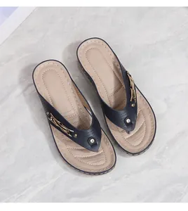 Detail of navy blue wedge flip-flops featuring laser-cut patterns and a golden metal buckle