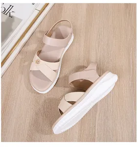 Close-up of beige platform sandals featuring crossed straps and gold metallic buckles