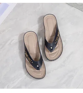Detail of navy blue wedge flip-flops with laser-cut straps and gold metal hardware