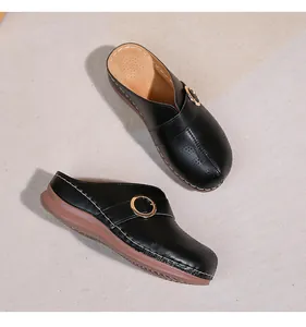 Vue détaillée de mules noires évidées avec boucle dorée et semelle compensée à couture latérale