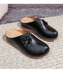 Detail of black hollow-out leather clogs with floral laser cut and non-slip platform sole
