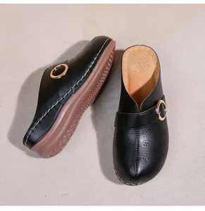 Détail du sabot en similicuir noir avec boucle dorée et motifs ajourés élégants