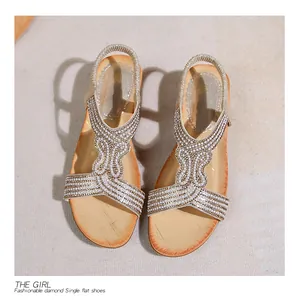 Vista dall'alto di sandali boho con decorazioni in perle e strass su tappeto in fibra