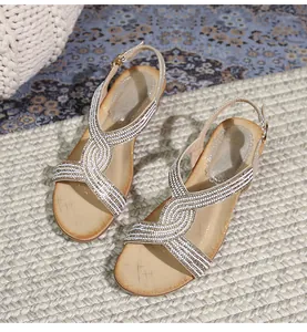 Détail de sandales compensées beige avec brides croisées en strass et boucle réglable
