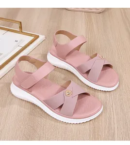 Detail of pink bohemian flat sandals featuring crisscross straps and metal button accents