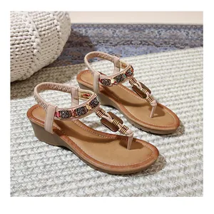 Detail view of Bohemian wedge sandals featuring floral metal charms and elastic back strap