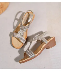 Dettaglio di sandali con zeppa boho con cinturini color champagne e perle decorative