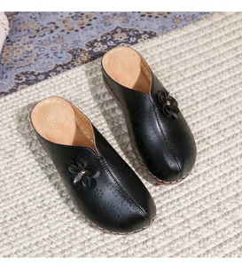 Close-up of black hollow-out mule shoes with floral decorations and white stitching details