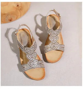 Nahaufnahme der champagner-goldenen Bohemian-Sandalen mit Herz-Strass und Perlen
