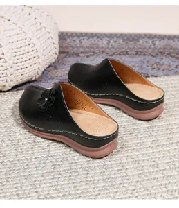 Detail of black wedge mule featuring laser-cut floral upper and stitched contrast sole