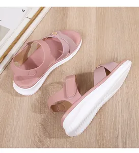 Detail view of pink platform sandals with cross straps and gold buckle on wood surface