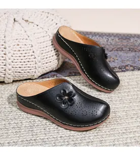 Detail of black hollowed-out mule sandals with leather flower and white stitching