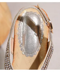 Detail der silbernen Keilsandalette mit perlenbesetzten Riemen und goldener Schnalle