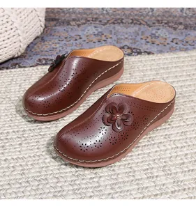 Detailed view of the laser-cut floral pattern and 3D flower on dark brown leather mule shoes