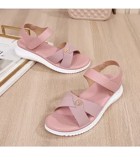 Detail of pink bohemian sandals with elastic straps and gold buckle on a white sole