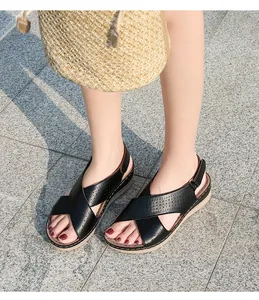 Close-up of black wedge sandals featuring laser-cut cross straps and beige platform sole