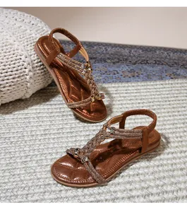 Λεπτομέρεια από φλατ σανδάλια boho με λαμπερά στρας και υφαντά λουράκια σε χάλκινο χρώμα