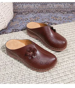 Detailed macro view of brown leather mule shoes featuring 3D floral and cutout patterns