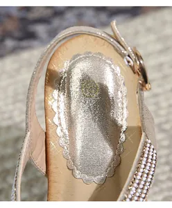 Détail de sandales champagne doré avec bordures ondulées et décorations de perles