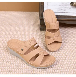 Detail view of beige wedge sandals with cutout straps, golden studs, and stitched insoles