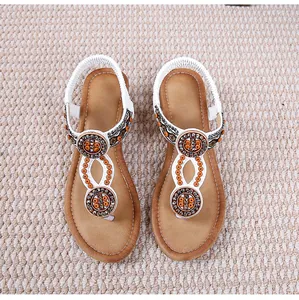 Dettaglio di sandali boho con zeppa, strass brillanti e decorazioni con perline arancioni