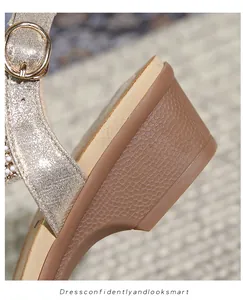 Détail de sandale pailletée or champagne avec boucle métal et talon compensé texturé