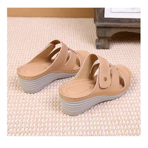 Close-up of the beige wedge sandal featuring hollow-out patterns and detailed stitching