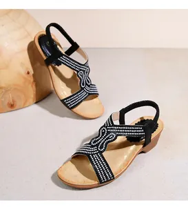 Dettaglio di sandali neri con zeppa bohémien con strass e suola con venature del legno