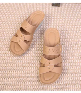 Detail of khaki wedge sandals with crisscross straps, rivets, and white stitching
