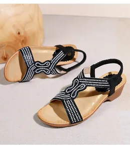 Dettaglio di sandali con zeppa neri boho con cinturini a pois e cinturino al tallone