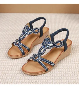 Close-up of bohemian wedge sandals with sparkling rhinestones and navy flower details