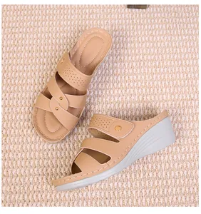 Detail of wedge sandals showing beige leather straps with gold studs and punch-out patterns