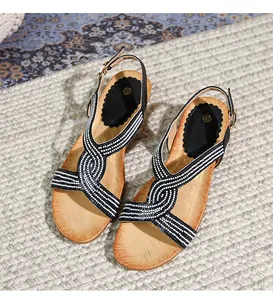 Détail de sandales compensées bohèmes avec strass et lanières croisées sur semelle bois