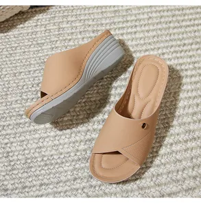 Detail of beige faux leather wedge sandals with decorative metal rivet and soft sole