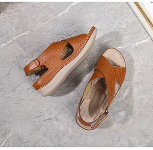 Detail of brown leather wedge sandals featuring laser-cut breathable patterns and stitching