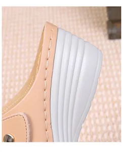 Detailed close-up of beige leather stitching and white wavy platform sole on women's sandal
