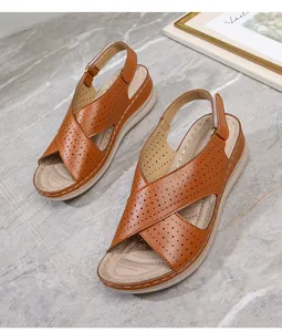 Close-up of brown cross-strap wedge sandals with laser-cut holes and thick white soles