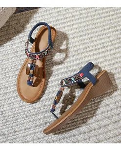 Close-up of Bohemian wedge sandals featuring colorful beads and floral metal ornaments