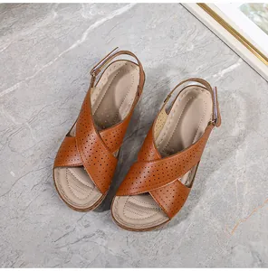 Top-down view of brown leather wedge sandals featuring laser-cut cross straps and adjustable back strap
