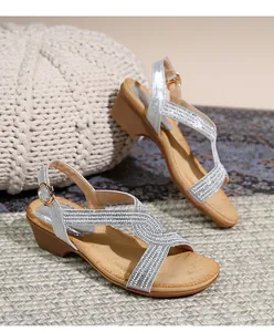 Détail de sandales compensées argentées à strass avec boucle de cheville dorée ajustable